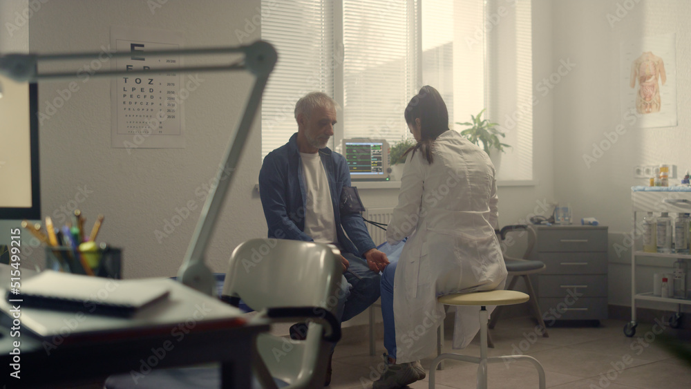 Medic putting cuff measuring pressure on senior patient arm. Healthcare concept. Medic putting cuff measuring pressure on senior patient arm. Healthcare concept.