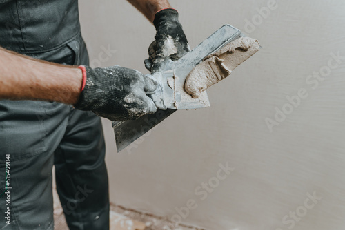Fototapet Builder in work overalls plastering a wall indoor