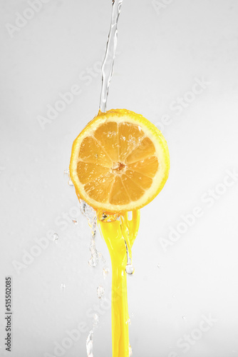lemon with a yellow fork and water drops on a light background