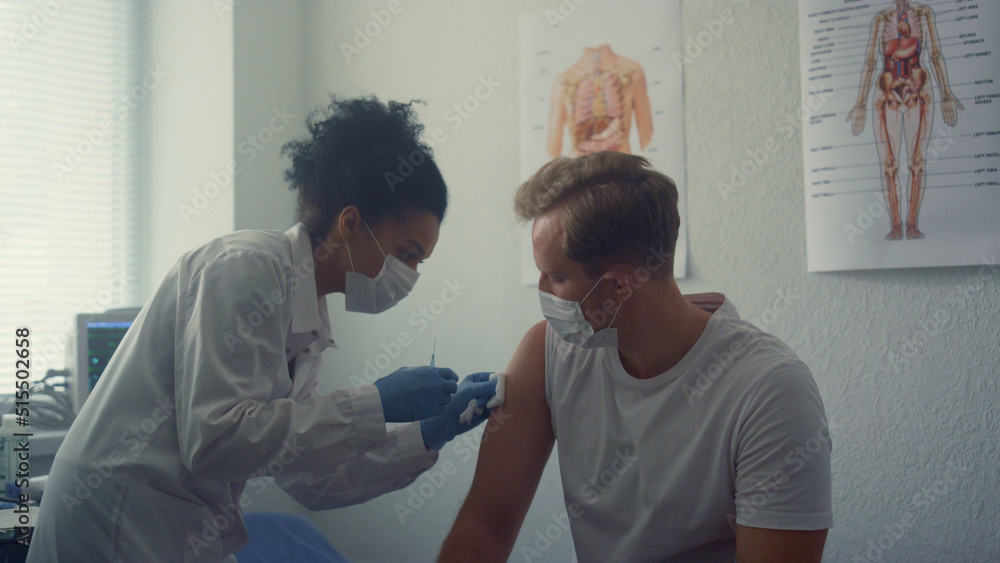Doctor vaccinating clinic client in office close up. Woman give injection to man Doctor vaccinating clinic client in office close up. Woman give injection to man
