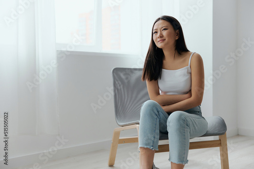 Pregnancy lost. Abortion high. Tormented suffering tanned beautiful young Asian woman hold hands on stomach at home interior living room. Injuries Poor health Illness concept. Cool offer Banner