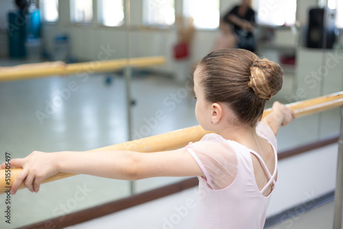 Lttle girl toddler ballerina in pale pink tutu and ballet shoes practicing dance moves.