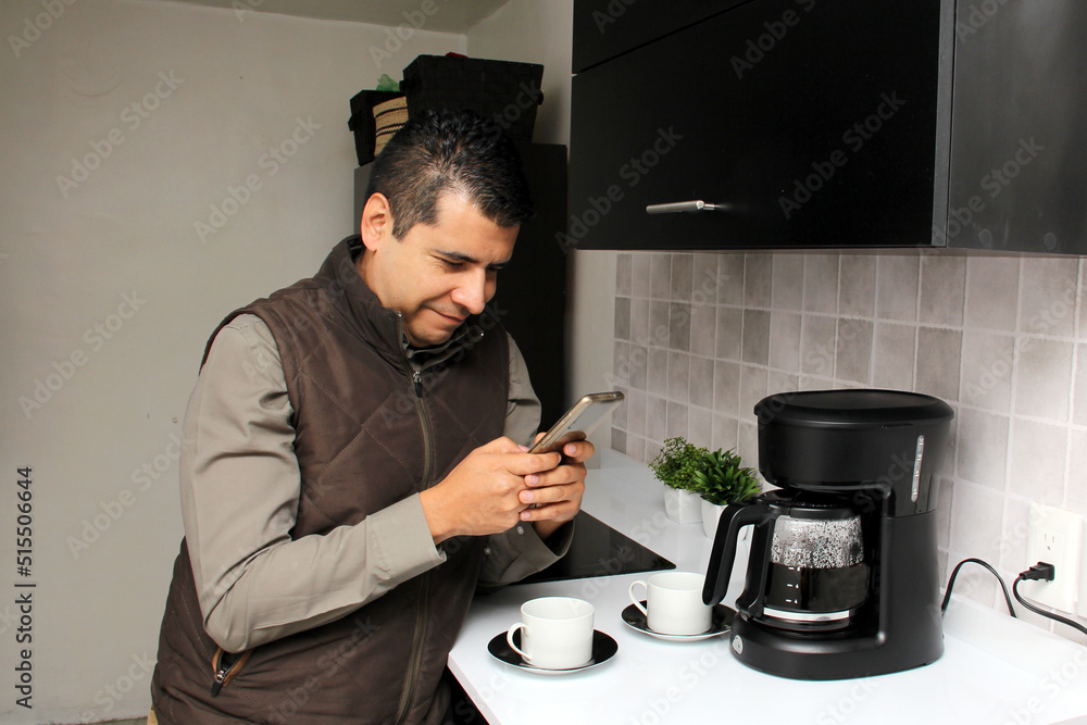 Latin adult man drinks freshly brewed coffee in the coffee maker in the kitchen of his home or office while using his cell phone to send messages, make calls at the beginning of the day
Latin adult man drinks freshly brewed coffee in the coffee maker in the kitchen of his home or office while using his cell phone to send messages, make calls at the beginning of the day