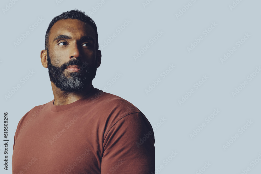 Obraz premium headshot portrait of a handsome thoughtful bearded mid adult man looking at copy space against gray background studio shot