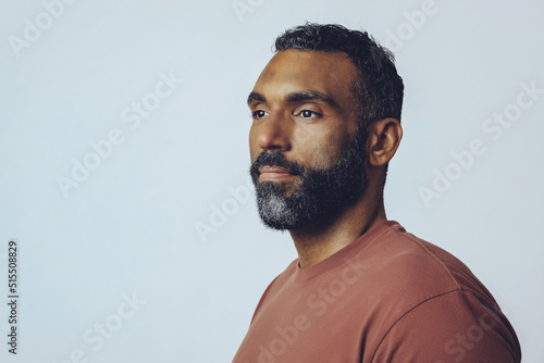 headshot portrait of a handsome bearded mid adult man looking away at copy space against gray background studio shot