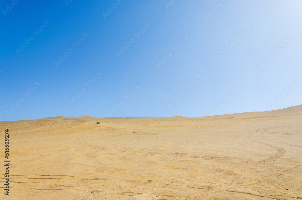 desert with car driving in background - Reserva nacional de Paracas