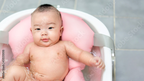 Asianmother give a bath newborn baby in a tiny bathtub in bathroom.