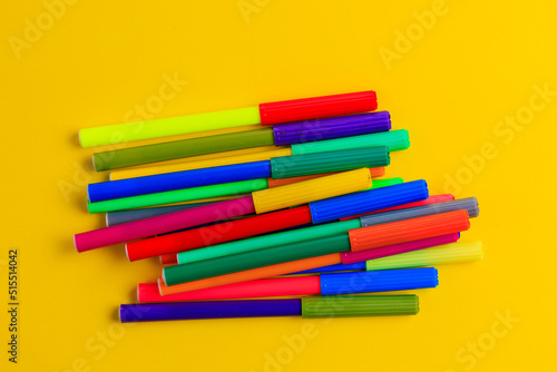 Multi-colored markers with mixed caps. Creative concept. Yellow background with selective focus and copy space photo