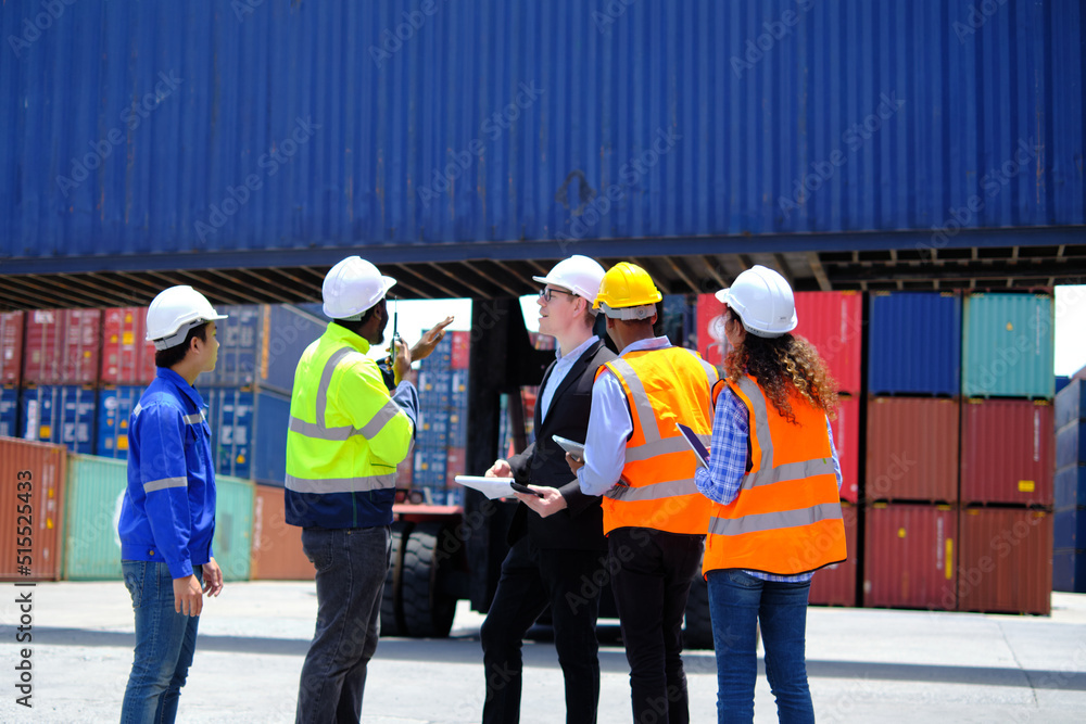 Group of multiracial workers in safety uniforms and hardhats work at logistics terminal dock with stacks of containers, loading control, and management shipping goods, cargo transportation industry. Group of multiracial workers in safety uniforms and hardhats work at logistics terminal dock with stacks of containers, loading control, and management shipping goods, cargo transportation industry.