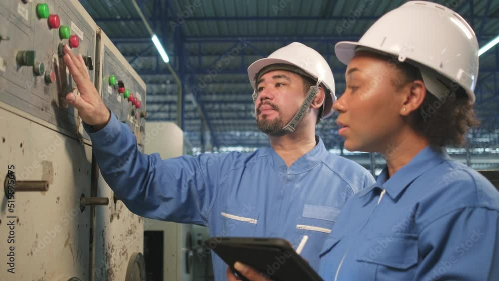 Professional industry engineer teams in hard hats and safety uniforms inspect machine's control panel, maintenance check with tablet in mechanical manufacture factory, electrical service occupation. Professional industry engineer teams in hard hats and safety uniforms inspect machine's control panel, maintenance check with tablet in mechanical manufacture factory, electrical service occupation.