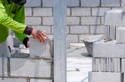 Cropped image of Asian builder worker making interior brick wall inside of house construction site