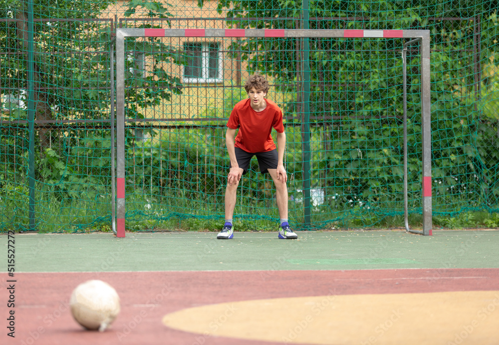 Teenager playing soccer. Playing football with a ball. Cute young boy player ready to play soccer on the indoor court. 