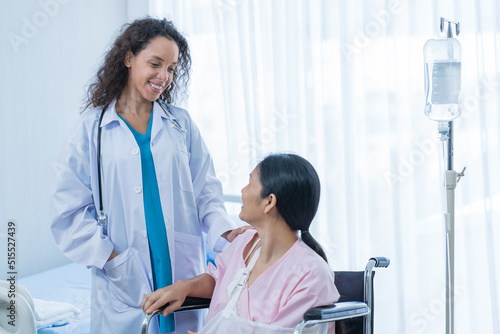 Asian young woman doctor support patient female sitting on wheelchair. 