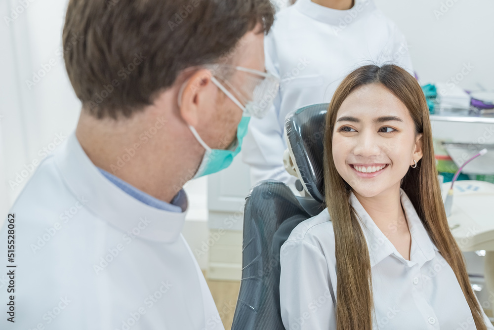 Asian beautiful girl talks and consult with Caucasian male dentist. Asian beautiful girl talks and consult with Caucasian male dentist.