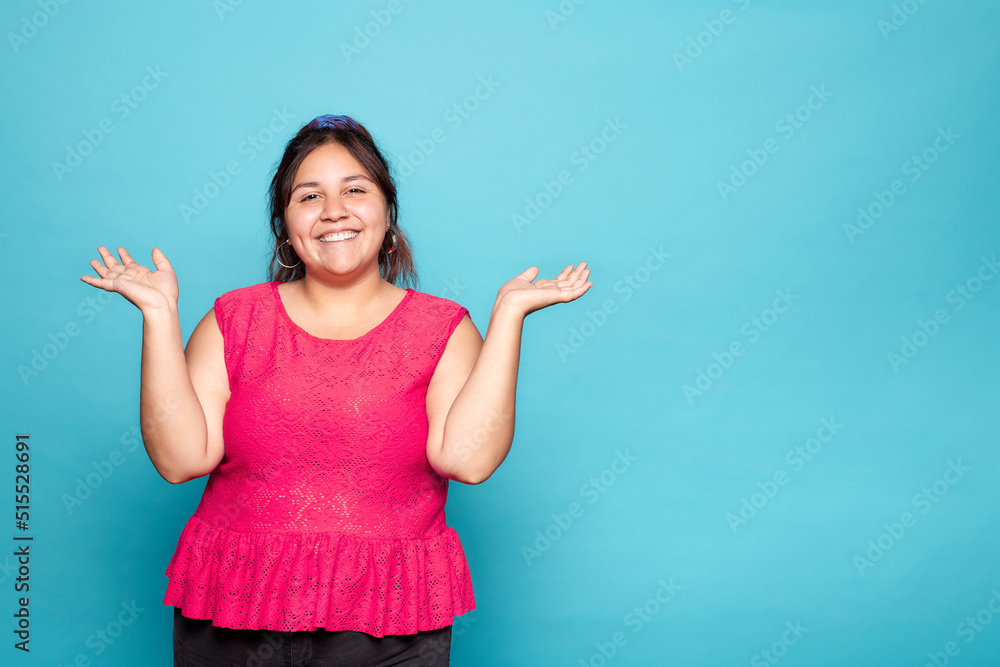 © Lux Images - Young curvy Latina woman smiling and presenting copy space for product with both hands open, isolated on blue background. © Lux Images - Young curvy Latina woman smiling and presenting copy space for product with both hands open, isolated on blue background.