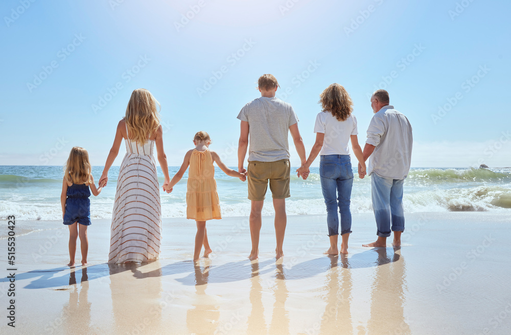 Rear view of family holding hands and having fun on a beach vacation together on a sunny day. Relatives enjoying summer and sunshine, bonding and spending quality time walking and feeling ocean water