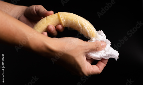 condom, hand hold banana with condom and tissue, sex education concept.