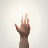A hand is touching a ray of light of hope for a religious worship message about faith and God.