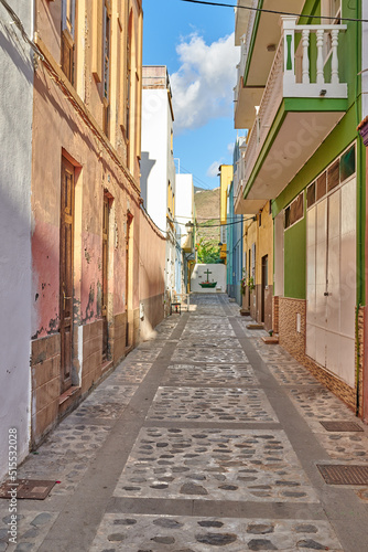 Fototapeta Naklejka Na Ścianę i Meble -  Empty cobbled street in a rural European tourist town. A quiet narrow alley way with colorful apartment buildings or houses. Hidden side street with traditional architecture in Santa Cruz de La Palma
