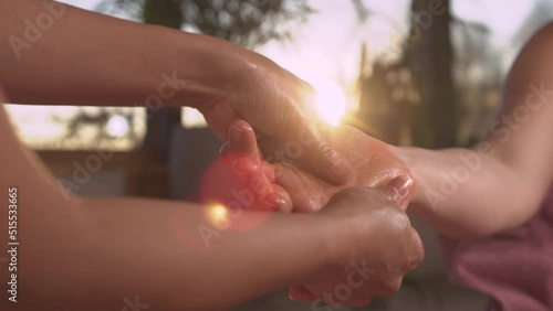 CLOSE UP: Hand reflexology massage for relaxation in beautiful golden sunlight. Sun shinning through massaging hands while performing reflexotherapy for stress relief and helping body work better. photo