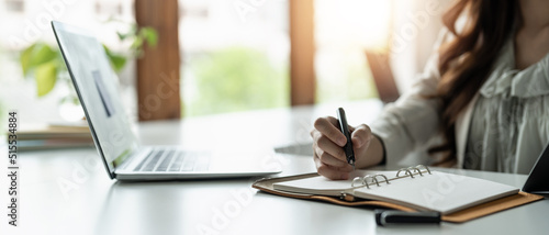 Close up of concentrated female student busy studying using laptop make notes in notebook, focused man worker employee write watching webinar or online training course on computer, education concept