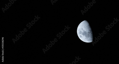 Close up of the half moon isolated against a came and peaceful black sky during midnight. A calm peaceful night of a brightly lit round sphere planet in the dark sky in a black galaxy or universe