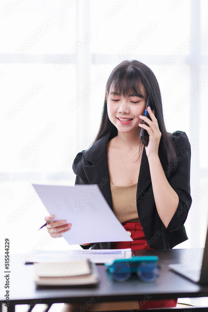 Smile business woman, Young Asian businesswoman talking on the phone using a laptop computer at the office. Smile business woman, Young Asian businesswoman talking on the phone using a laptop computer at the office.