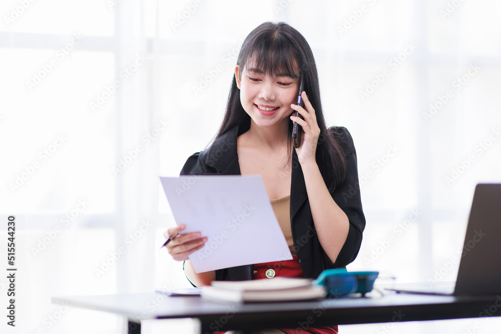 Smile business woman, Young Asian businesswoman talking on the phone using a laptop computer at the office. Smile business woman, Young Asian businesswoman talking on the phone using a laptop computer at the office.