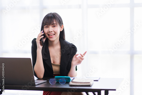 Smile business woman, Young Asian businesswoman talking on the phone using a laptop computer at the office.
