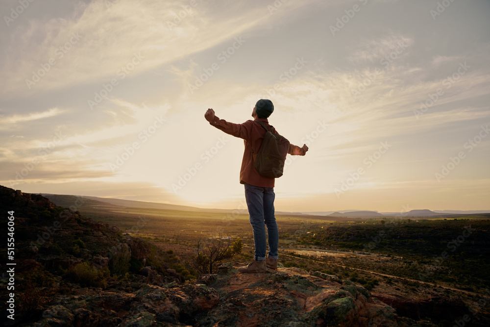 Young man with backpack standing on mountain with hands outstretched Young man with backpack standing on mountain with hands outstretched