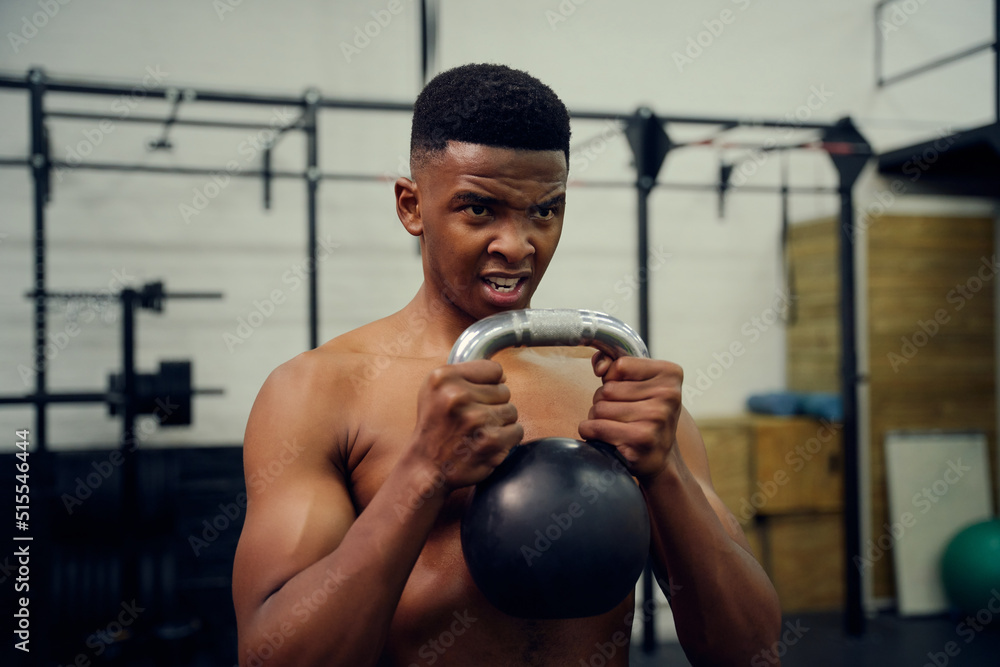 African American male doing cross fit in gym. Mixed race male using a kettlebell during exercise. High quality photo African American male doing cross fit in gym. Mixed race male using a kettlebell during exercise. High quality photo