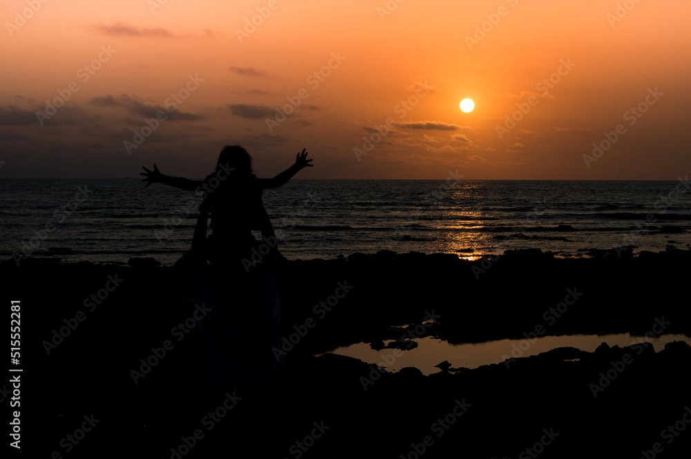 Une petite fille très heureuse les bras écartés qui regarde un superbe coucher de soleil Une petite fille très heureuse les bras écartés qui regarde un superbe coucher de soleil
