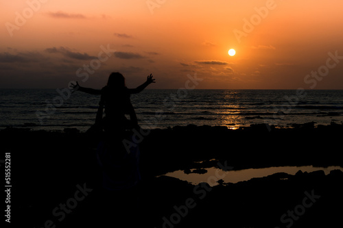 Une petite fille très heureuse les bras écartés qui regarde un superbe coucher de soleil photo