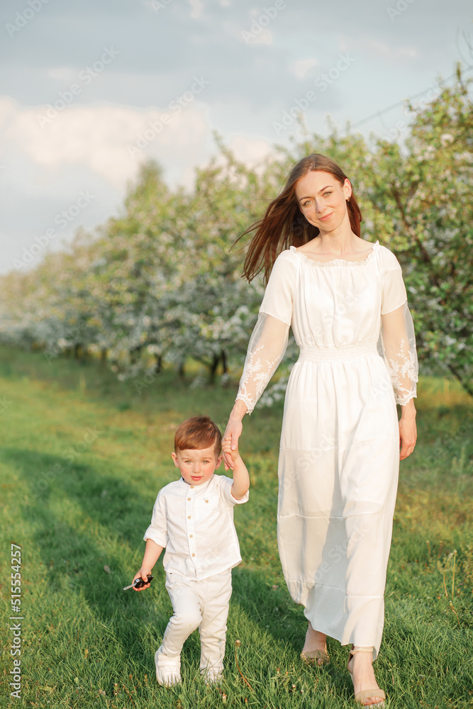Portrait of happy mother and her baby boy. Beautiful touching scene of mom and son. Blooming garden in spring. Portrait of happy mother and her baby boy. Beautiful touching scene of mom and son. Blooming garden in spring.