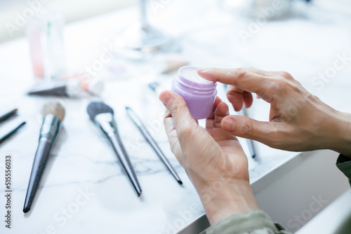 Woman hand touch moisturizer white cream in jar