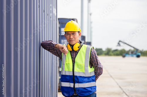 Relaxing engineer man in industry containers cargo, Foreman dock worker in hardhat and safety vest control loading containers box from cargo