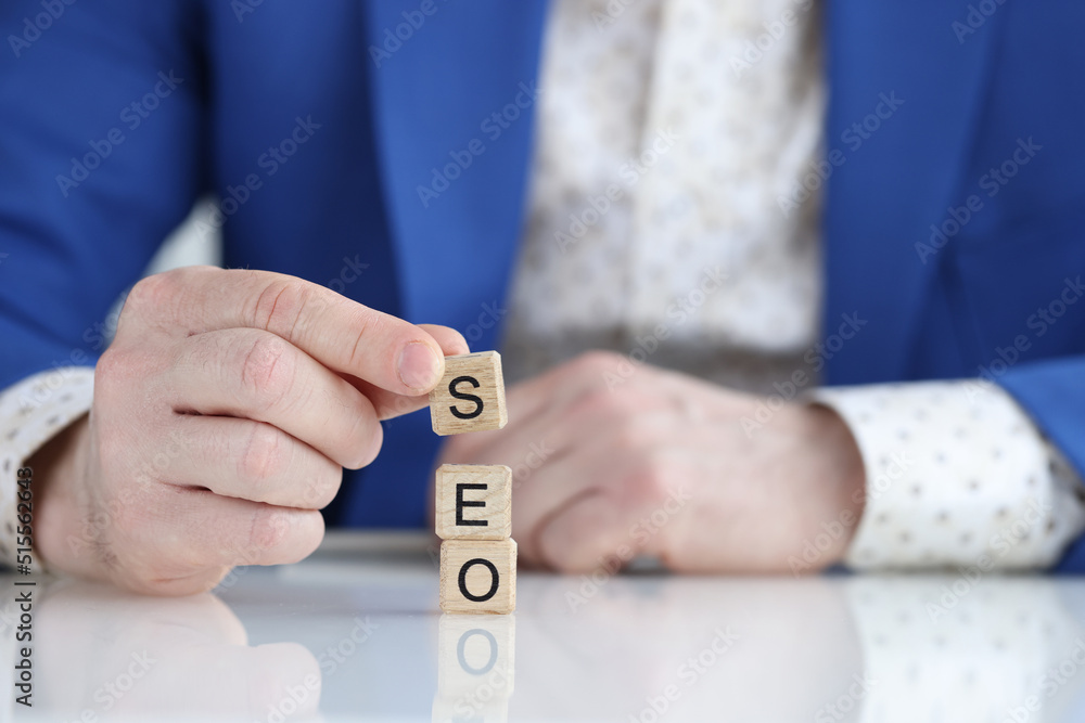 Businessman collecting words seo with wooden cubes