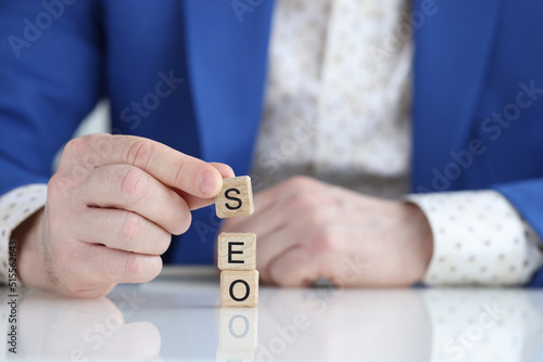Businessman collecting words seo with wooden cubes