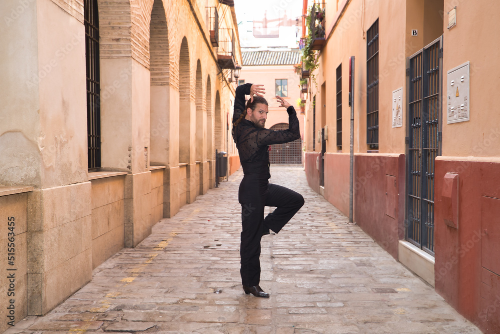 Young man with beard and ponytail, wearing black transparent shirt with black polka dots, black pants and jacket, dancing flamenco in the city. Concept art, dance, culture, tradition. Young man with beard and ponytail, wearing black transparent shirt with black polka dots, black pants and jacket, dancing flamenco in the city. Concept art, dance, culture, tradition.