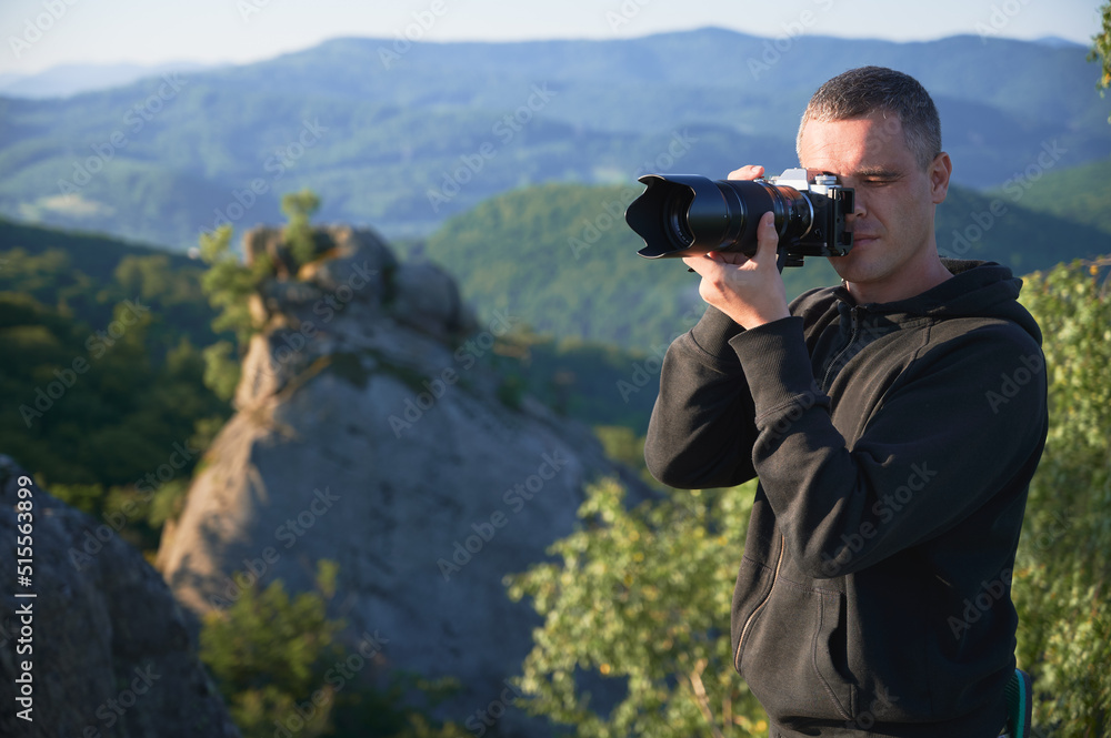 Nature photographer with digital camera on top of the mountain in the morning, taking photo of sunset mountains. Concept of travel lifestyle. Nature photographer with digital camera on top of the mountain in the morning, taking photo of sunset mountains. Concept of travel lifestyle.