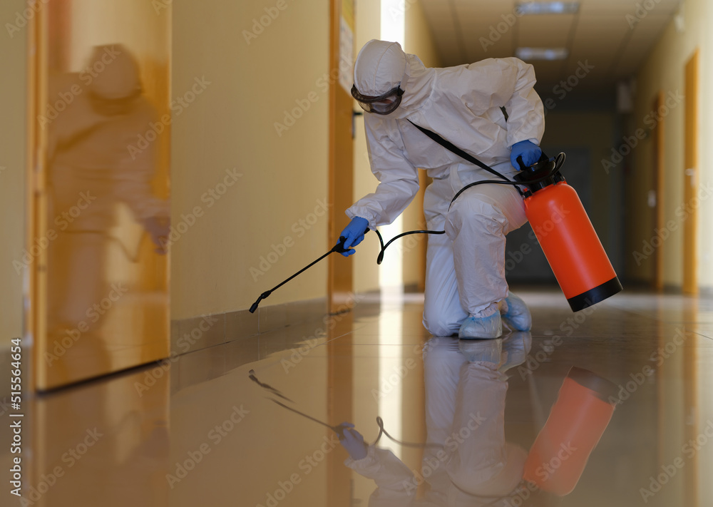 Person in protective suit disinfects office and corridors to prevent spread of COVID-19