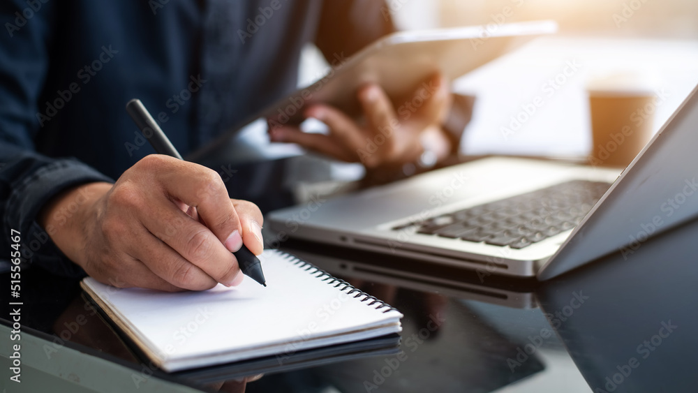 Young professional businessman writing his idea concepts on notebook while working on his project. Young professional businessman writing his idea concepts on notebook while working on his project.