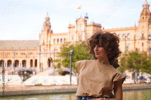 beautiful woman with curly hair is on holiday in sevilla. The woman is posing for pictures in front of the most famous square of the centuries old city. Holiday and travel concept. © @skuder_photographer