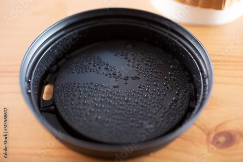 A closeup view of condensation bubbles building up on the under side of a coffee lid.