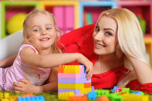 young mother and little daughter playing blocks game