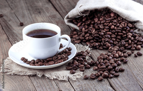 Cup of coffee with scattered coffee beans on a wooden background.