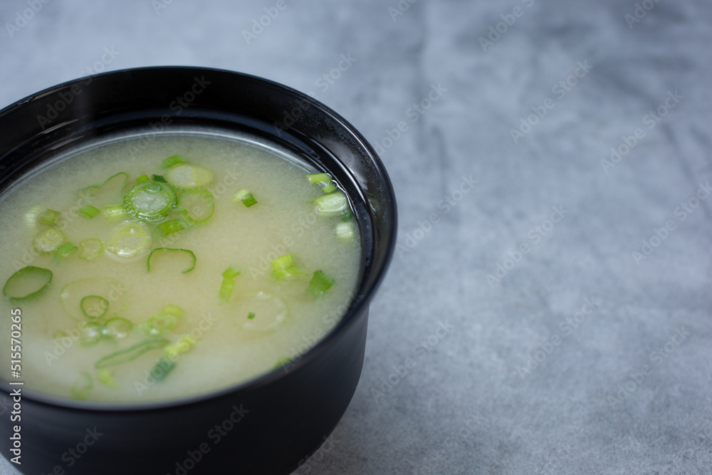 A view of a bowl of miso soup, on the left side of the frame. A view of a bowl of miso soup, on the left side of the frame.