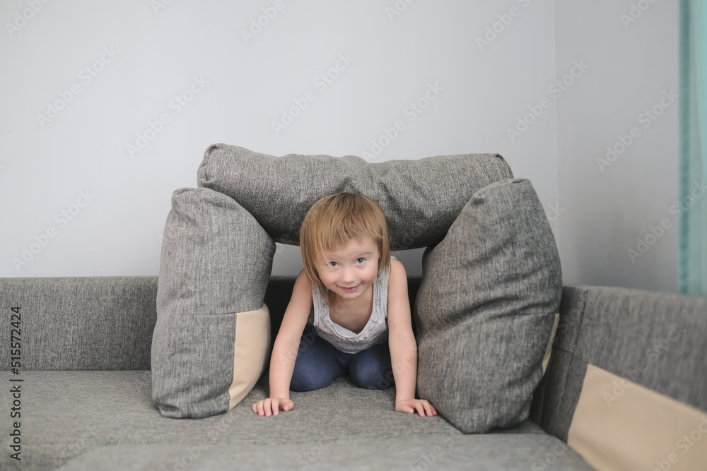 funny European child playing with pillows on couch funny European child playing with pillows on couch