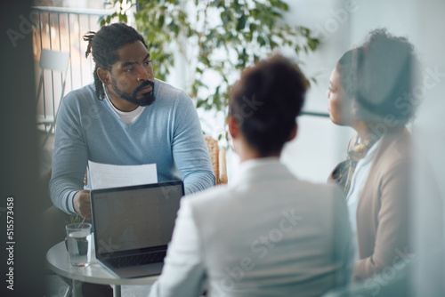 Konstfotografi Young African American man holds his resume while talking during job interview in office