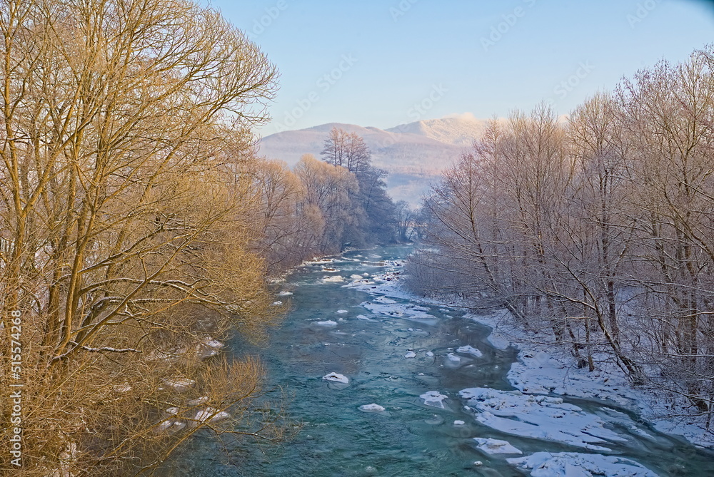 In winter, the unfrozen riverbed in the snow-covered banks. winter background In winter, the unfrozen riverbed in the snow-covered banks. winter background